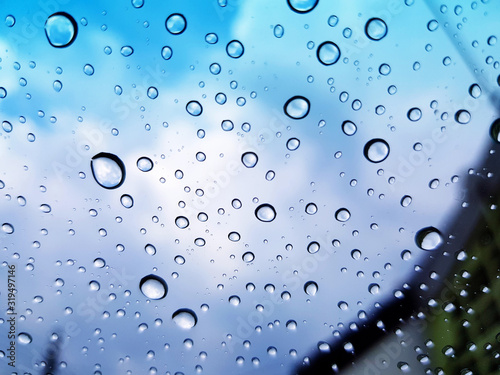 May raining or water droplet  on glass with building, blue sky and cloud background concept. Beautiful of nature and season 