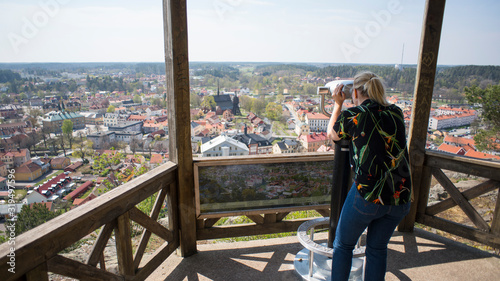 Obraz na płótnie Tourist woman using binoculars on lookout point overlooking City of Soderkoping in Sweden, Europe