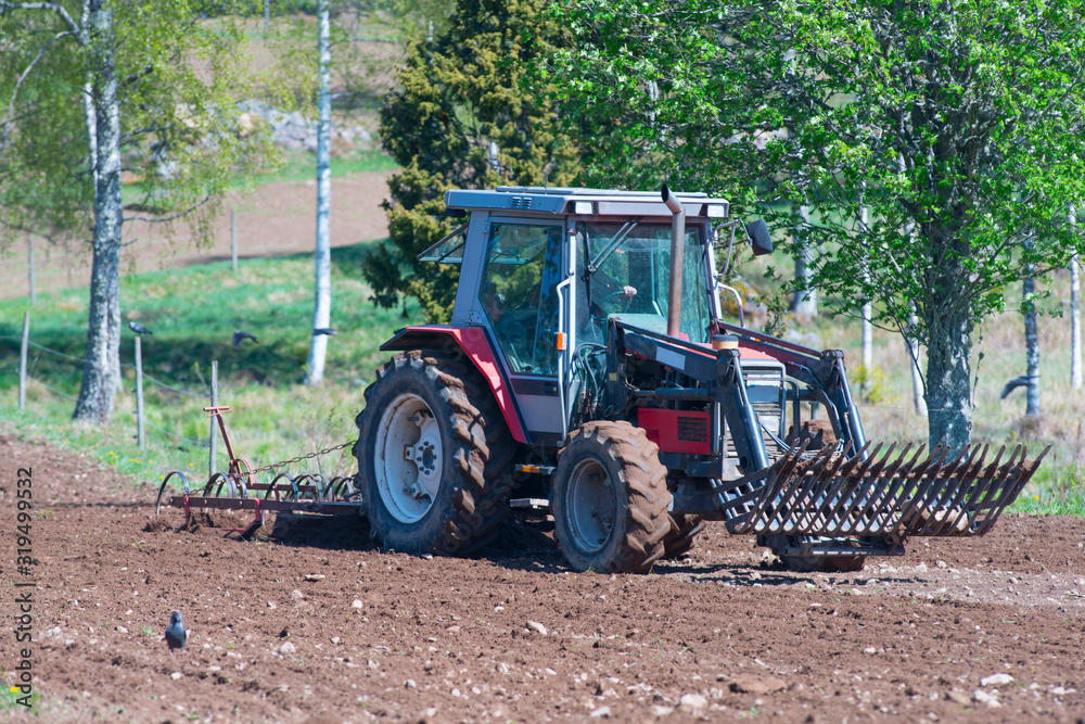 Tractor cultivating field at rural farm - Farming vehicle in action on field - Farmer in work. Tractor cultivating field at rural farm - Farming vehicle in action on field - Farmer in work.