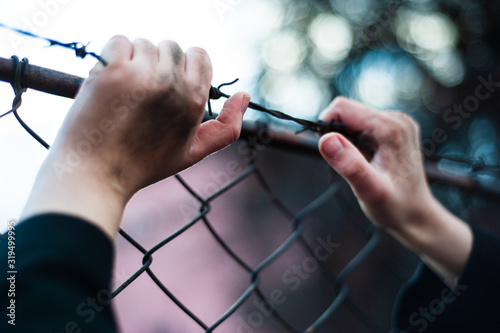 Photography The migrant is holding his hands behind the protective fence