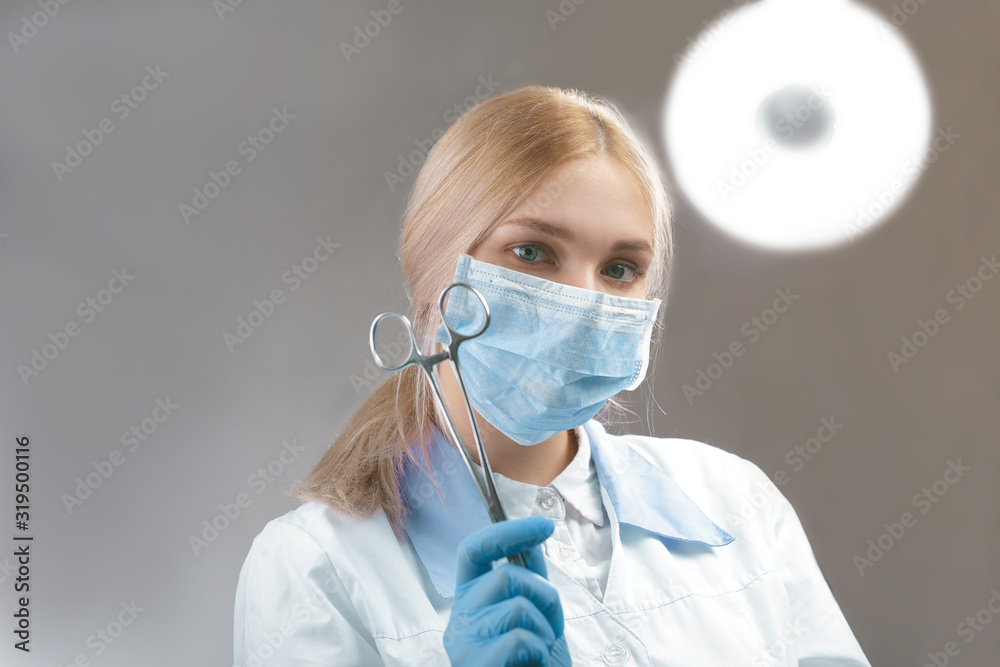 surgeon girl stands with a clip in her hands against the background of the lamp surgeon girl stands with a clip in her hands against the background of the lamp