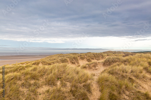 Looking out over marram grass covered sand dunes towards the sea  at Formby in Merseyside