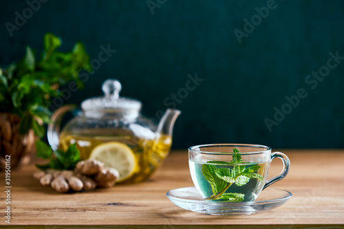 Fresh mint herbal tea in glass teapot and cup, front view