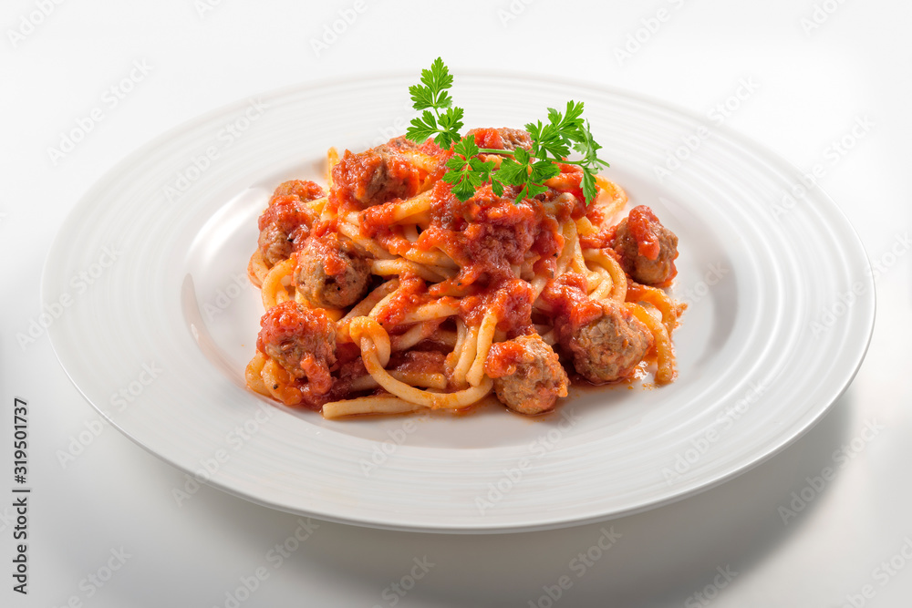 Plate of spaghetti with tomato and meatballs with parsley leaves