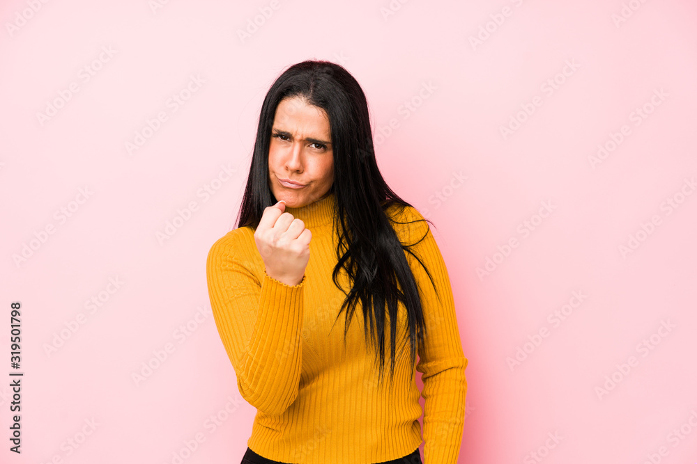 Young caucasian woman isolated on a pink background showing fist to camera, aggressive facial expression.