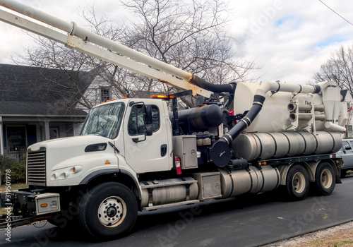 Vacuum truck sewer and cleaner parked on residential neighborhood street.