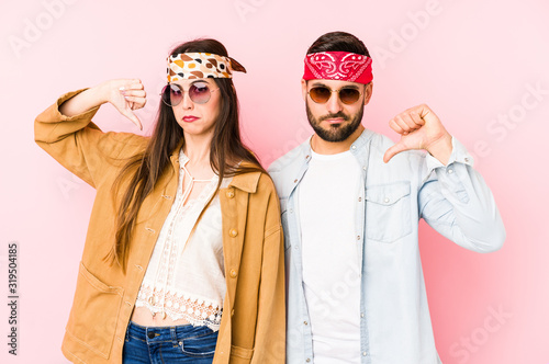 Young caucasian couple wearing a music festival clothes isolated showing a dislike gesture, thumbs down. Disagreement concept.