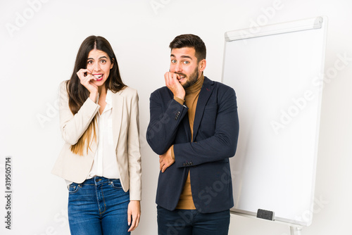 Young caucasian business couple isolated biting fingernails, nervous and very anxious.