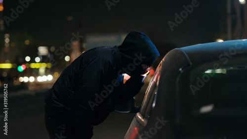 Canvas Print Robber man shines a flashlight in a car stealing at night crime male thief illeg