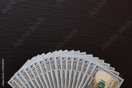fan of 100 dollar banknotes on slate tray