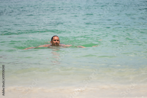 A man swims in the waves of the sea or ocean in a tropical resort and relaxes and enjoys