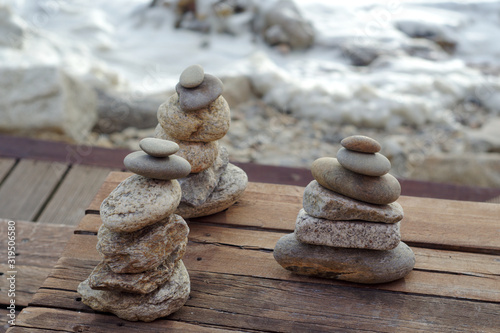 Three piles of Zen stones on a wooden floor at the Atlantic ocean sandy beach. Gondarém beach, Porto, Portugal.
