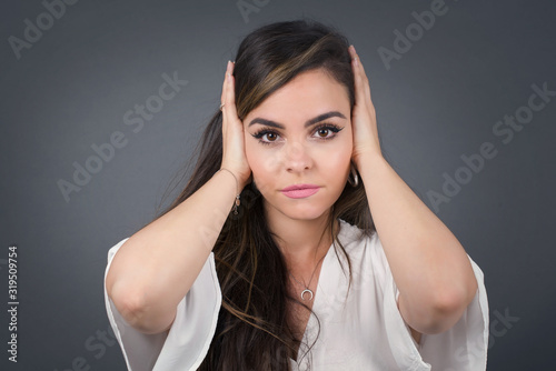 Woman plugging ears with hands does not wanting to listen hard rock or loud music. European Young female ignoring noise or din covering her ears with hands avoiding loud sounds at street.