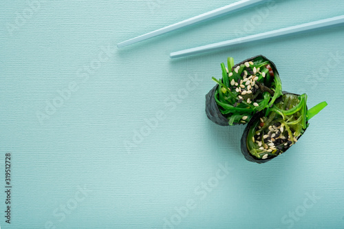 Two Chuka seaweed Sushi with chopsticks on a blue background, top view photo