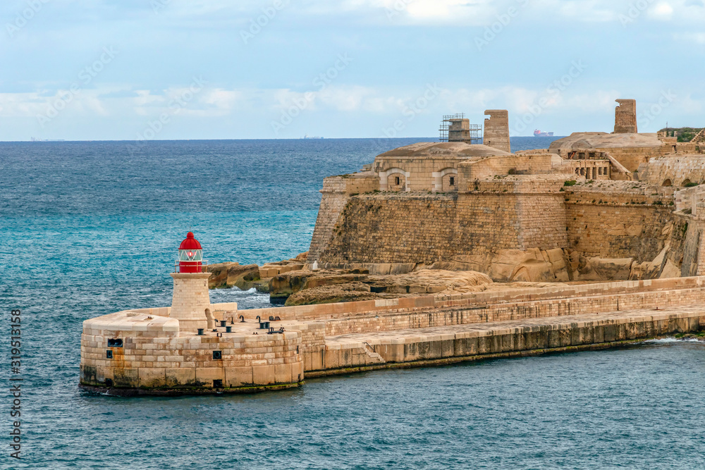 Old lighthouse and breakwater bridge of Fort Ricasoli from Valletta in Malta