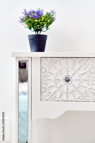 Living room detail design stylish luxury furniture floral ornate carving art of bedside table violet natural flower potted plant on it. Background element close up view, no people photo