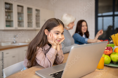Daughter looking at a laptop at a table in the kitchen.