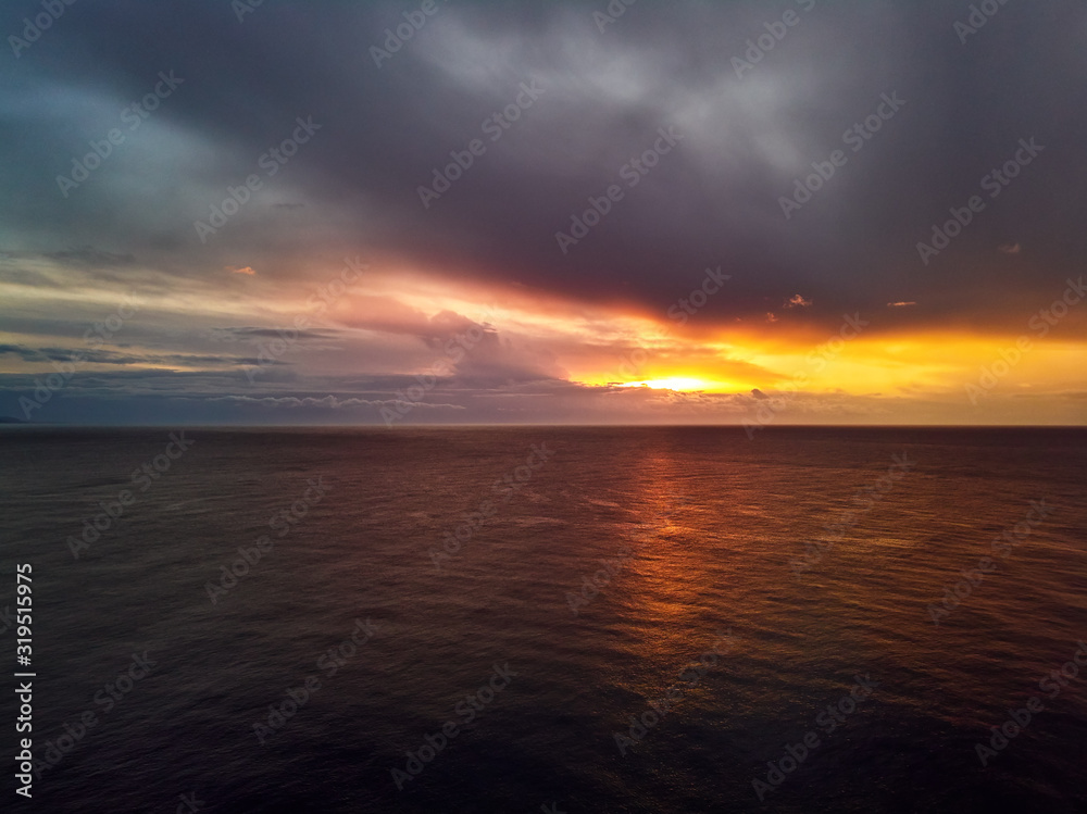 Bright colourful sunset with gloomy cloudy sky over Mediterranean Sea calm smooth waters. Spain, Costa Blanca
