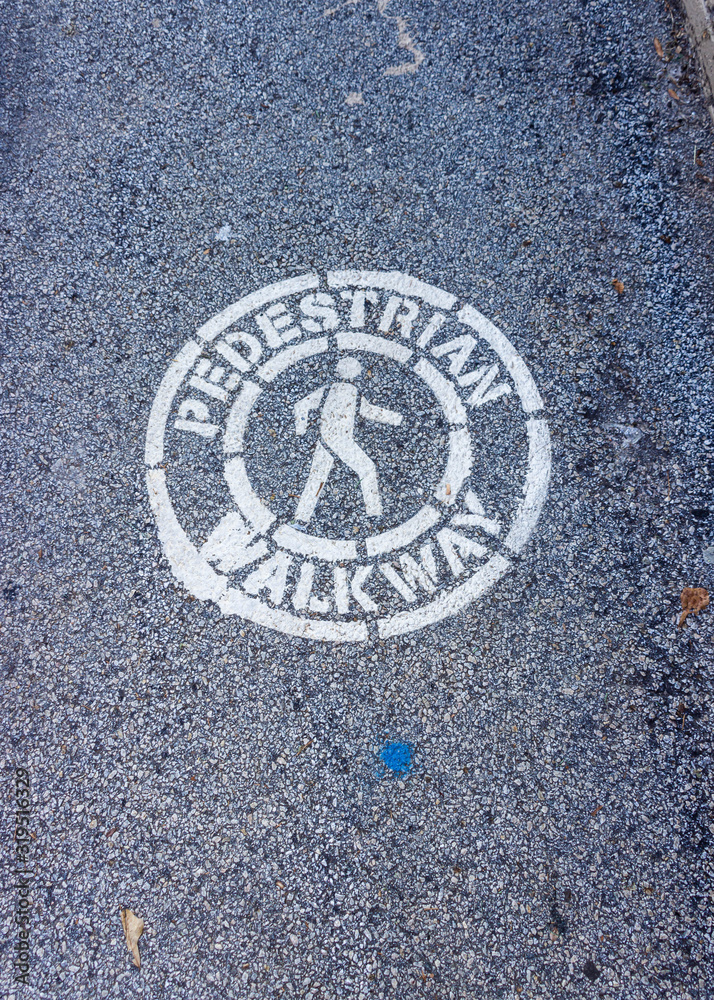 A pedestrial walkway symbol is painted on an asphalt road.
