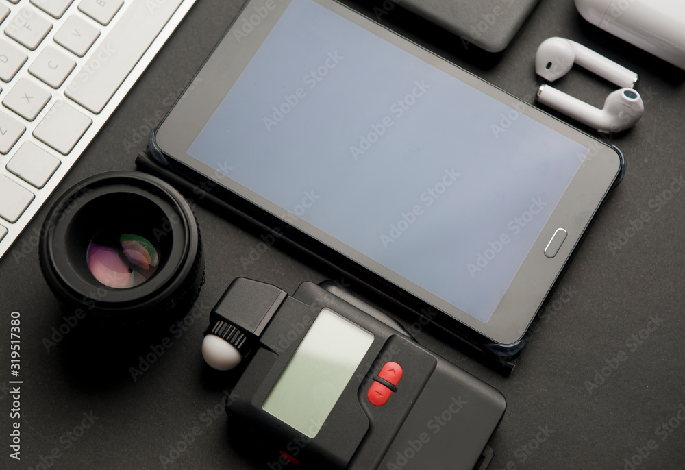 close-up, photography accessories photography objective, with photometer, electronic agenda, headphones, white computer keyboard, partial view black hard disk, white charger, on black background close-up, photography accessories photography objective, with photometer, electronic agenda, headphones, white computer keyboard, partial view black hard disk, white charger, on black background