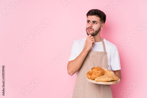 Young caucasian baker man isolated looking sideways with doubtful and skeptical expression.