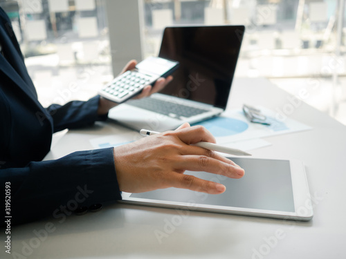 Business woman hand working at a computer  using calculator and laptop to calculate an account. Finance and accounting concept.