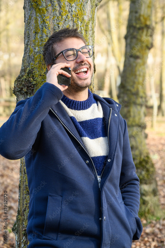 Smiling man, talking on mobile phone in an autumn park . Smiling man, talking on mobile phone in an autumn park .