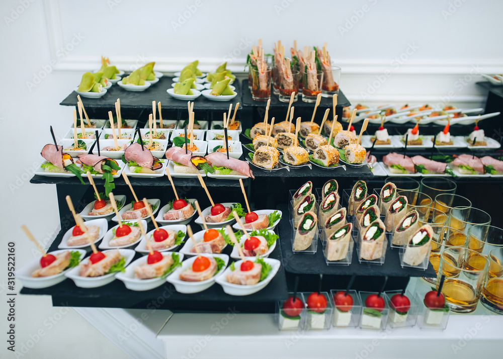 Buffet of different delicious food at a wedding celebration. Goodies for guests. Wedding party. Canapes, sushi, fruit, meat, drink, champagne, wine, juice.