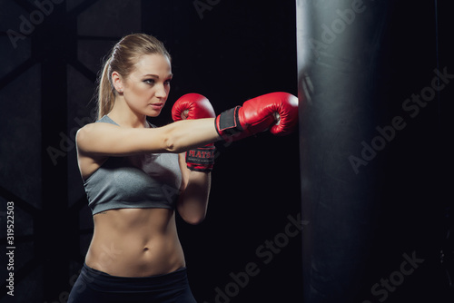 Woman in boxing gloves near a punching bag..