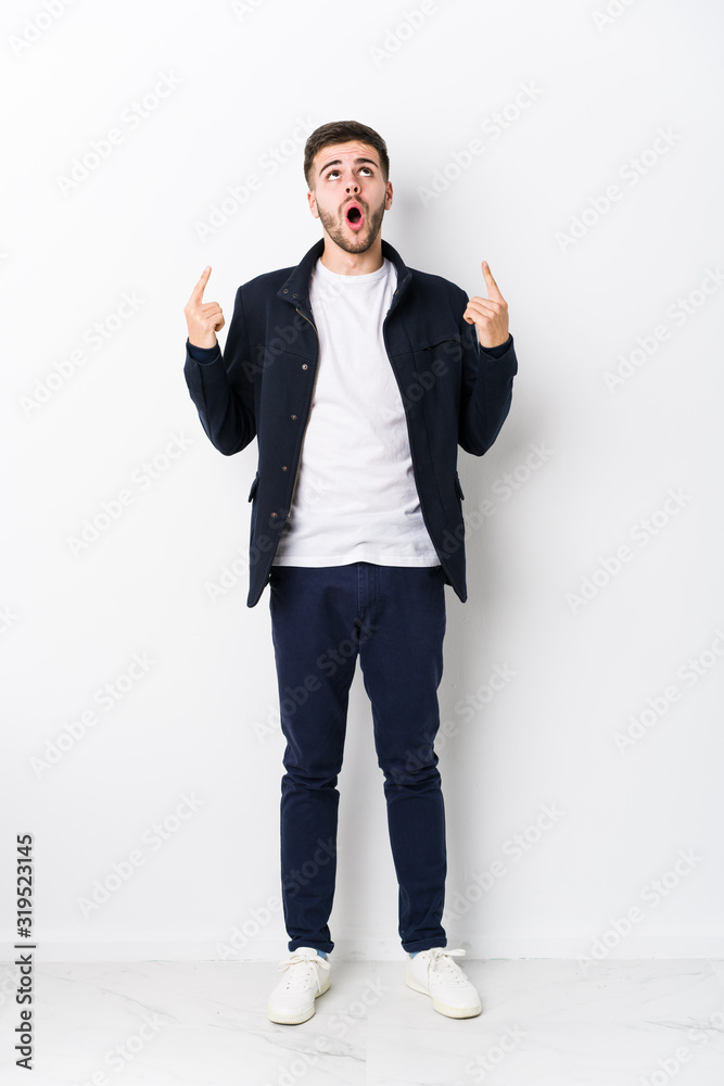 Full body young caucasian man isolated pointing upside with opened mouth. Full body young caucasian man isolated pointing upside with opened mouth.