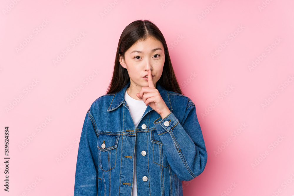 Young chinese woman posing in a pink background isolated keeping a secret or asking for silence. Young chinese woman posing in a pink background isolated keeping a secret or asking for silence.