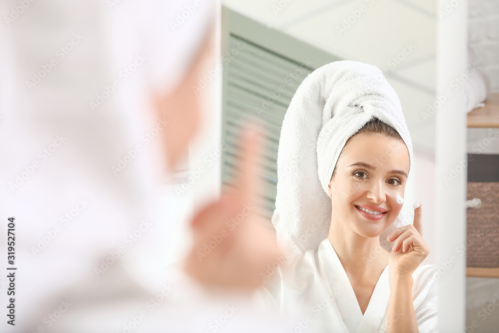 Beautiful young woman applying cream at home Beautiful young woman applying cream at home