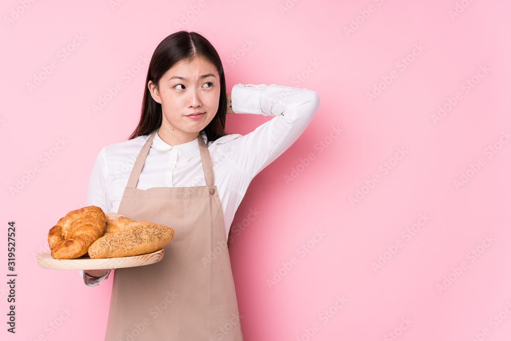 Young chinese baker woman isolated touching back of head, thinking and making a choice. Young chinese baker woman isolated touching back of head, thinking and making a choice.