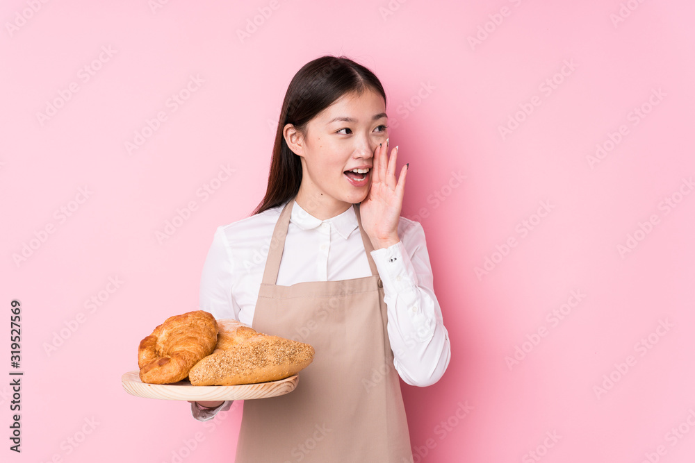 Young chinese baker woman isolated shouting and holding palm near opened mouth. Young chinese baker woman isolated shouting and holding palm near opened mouth.