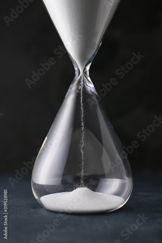 Hourglass on dark background. Time management concept photo