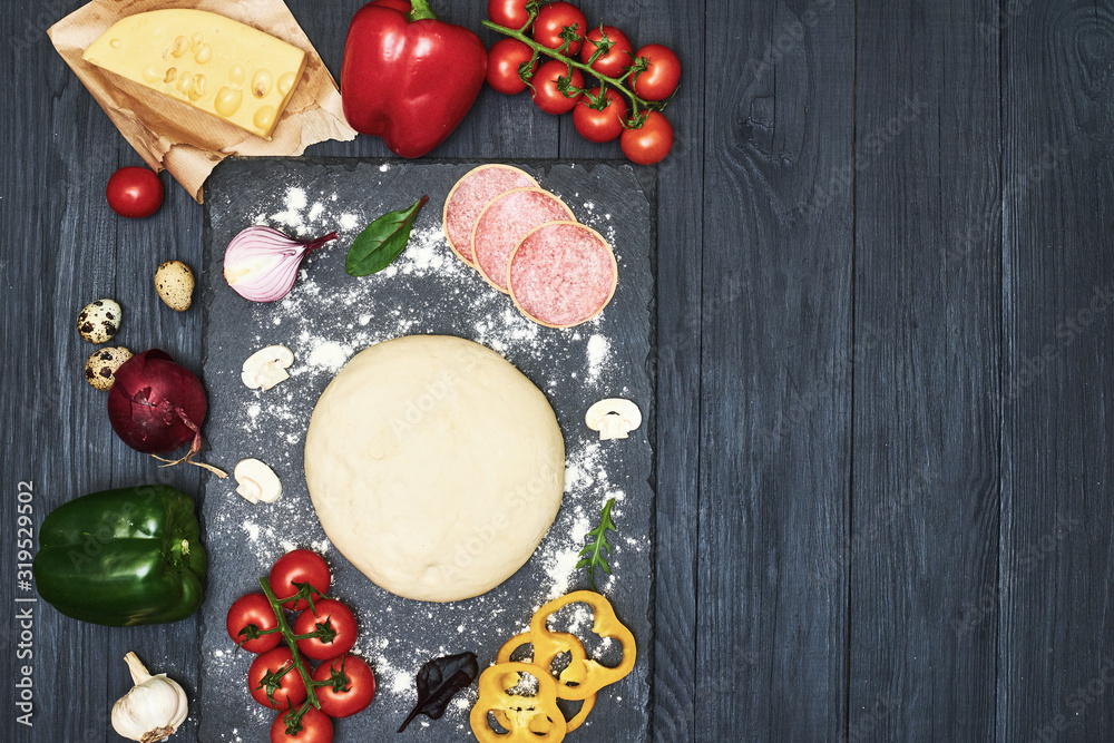 Pizza dough with ingredients on a dark background. Place for text. Pizza dough with ingredients on a dark background. Place for text.