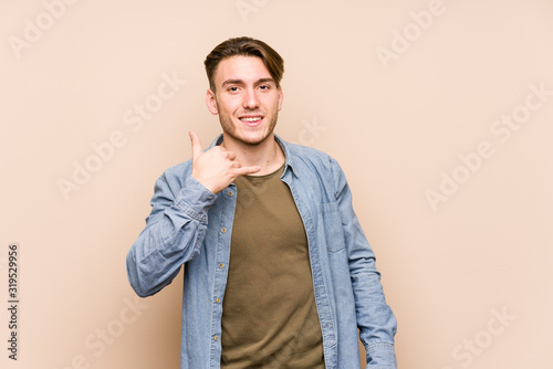 Young caucasian man posing isolated showing a mobile phone call gesture with fingers.