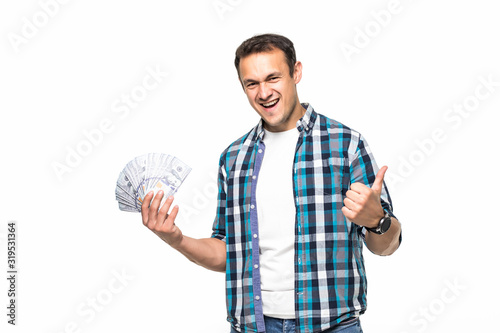 Happy winner man in casual t-shirt smiling with money in dollar banknotes isolated over white background