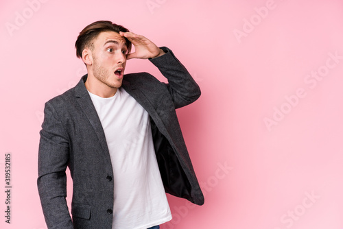 Young caucasian business man posing isolated looking far away keeping hand on forehead.