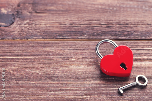 Valentine heart shaped padlock with key on brown wooden table