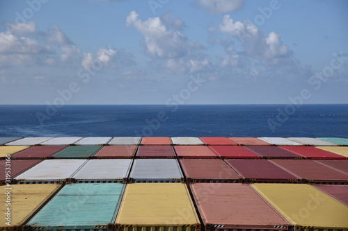 Containers loaded on the cargo container ship, she is sailing through calm blue sea.