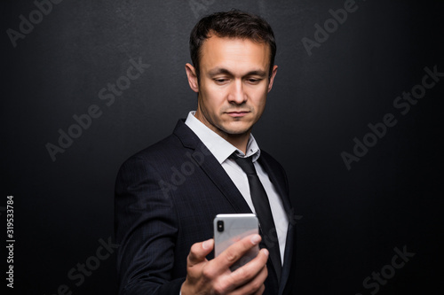 Portrait of cheerful businessman in suit surfing in internet Isolated on black background.