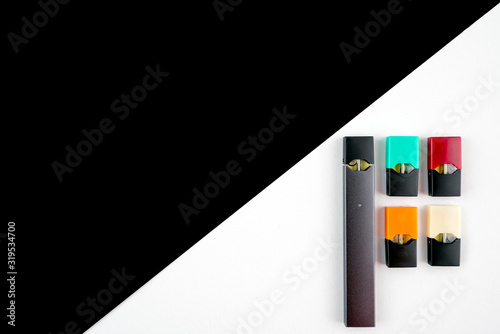 Vaping device and colored vaping pods on black and white diagonal background. Technology and nicotine concept..High end product photography theme with copy space for text. photo