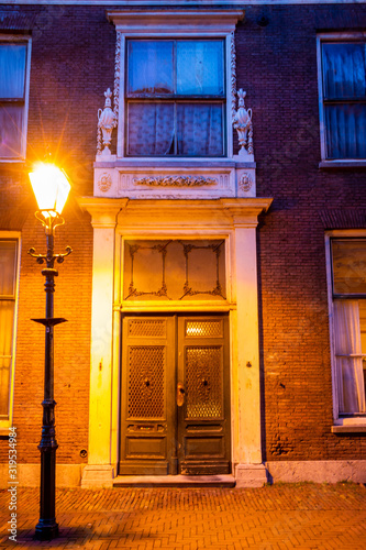Old antique door in Schiedam a city in South Holland, photo taken in the evening with evening light from a lamppost