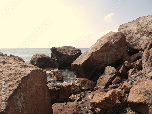 Landscape with cliffs and large stones on the coast near Akrotiri. Santorini, Greece.