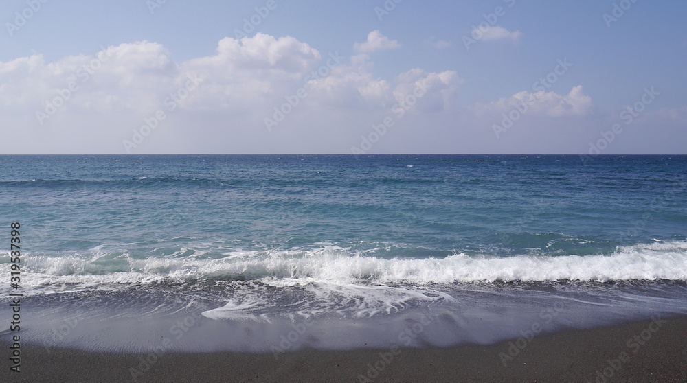 Seascape on the island of Santorini, Greece. Sea waves with foam on a sunny day.