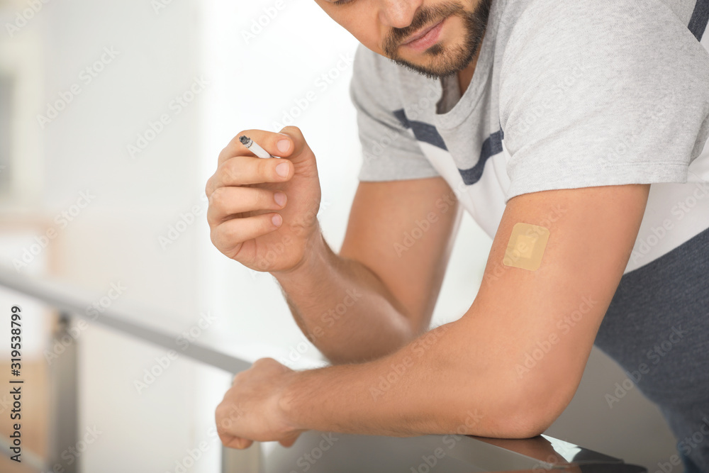 Man with nicotine patch and cigarette indoors, closeup