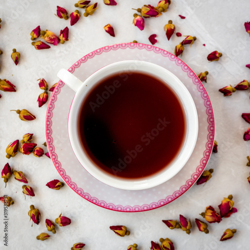 Top view of a cup of tea with dried roses 