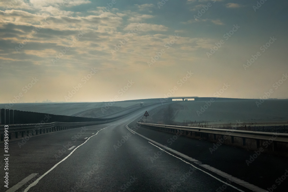 Asphalt highway in foggy cloudy winter morning
