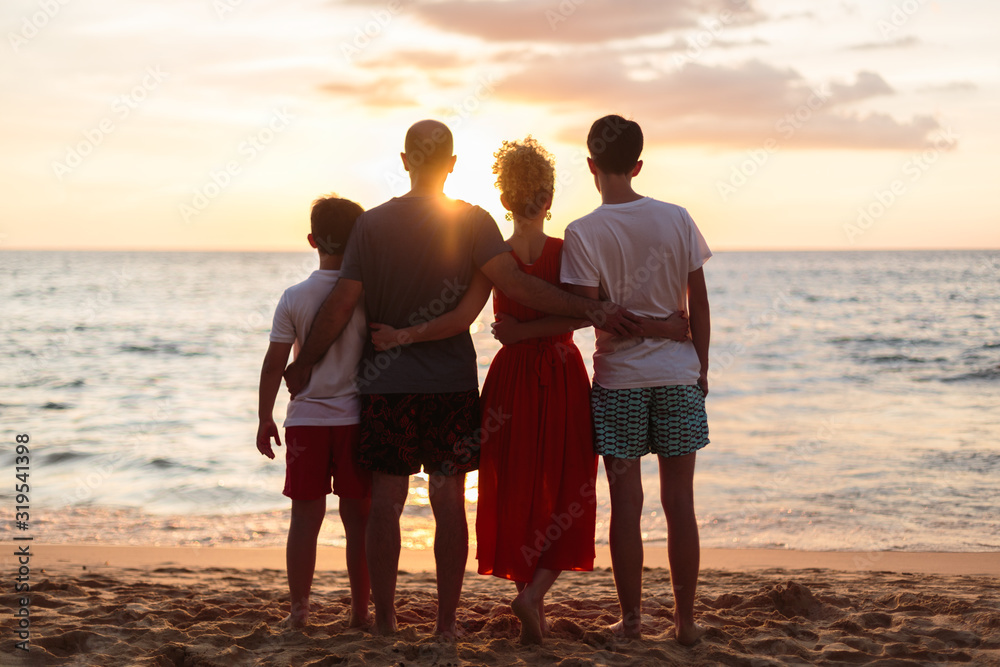 Happy family standing on the beach on the dawn time